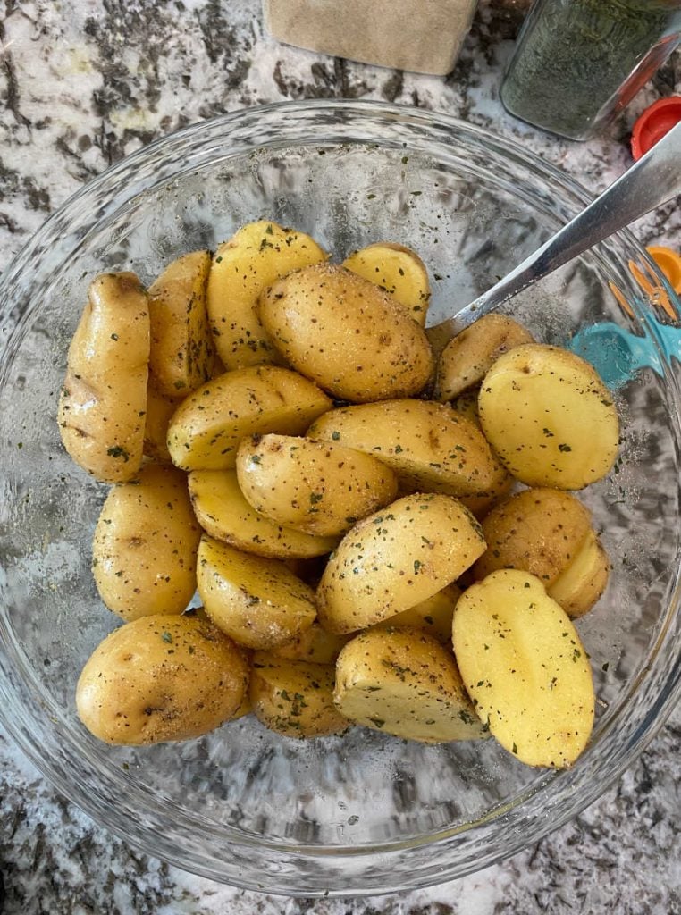seasoned baby potatoes cut in half in mixing bowl