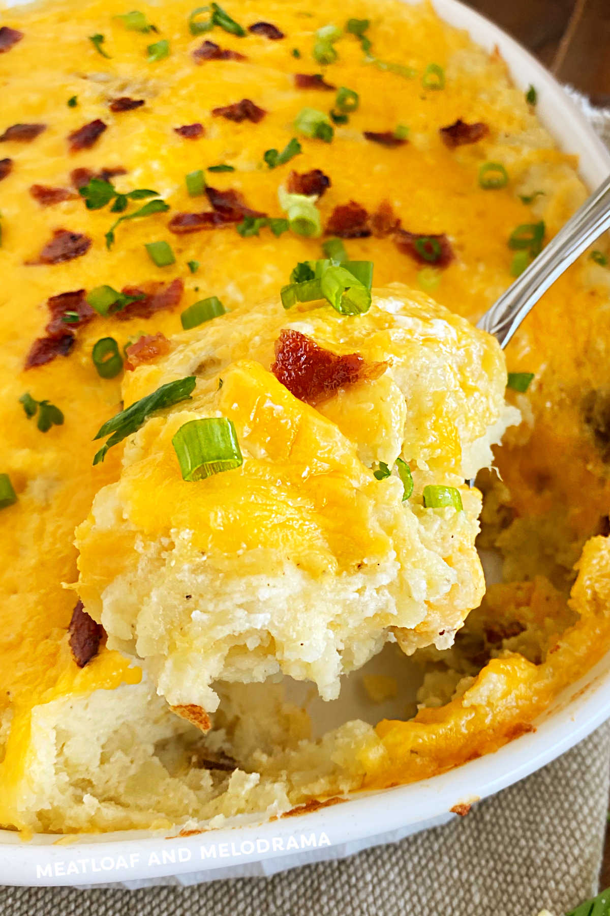 twice baked potatoes casserole topped with cheddar cheese and bacon on a serving spoon