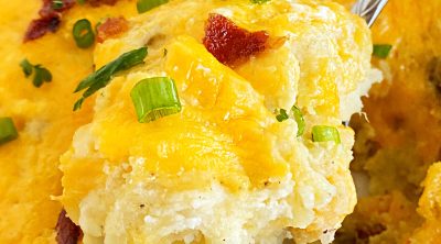 twice baked potatoes casserole with cheddar, bacon and green onions on a serving spoon
