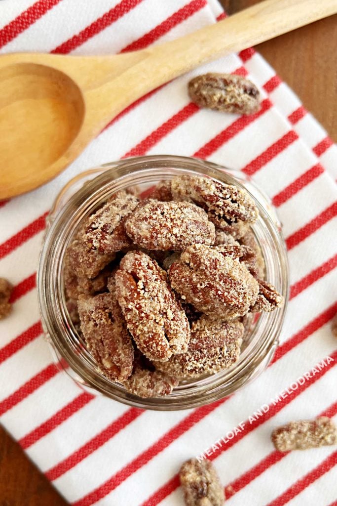 overhead view of candied pecans in mason jar with wooden spoon