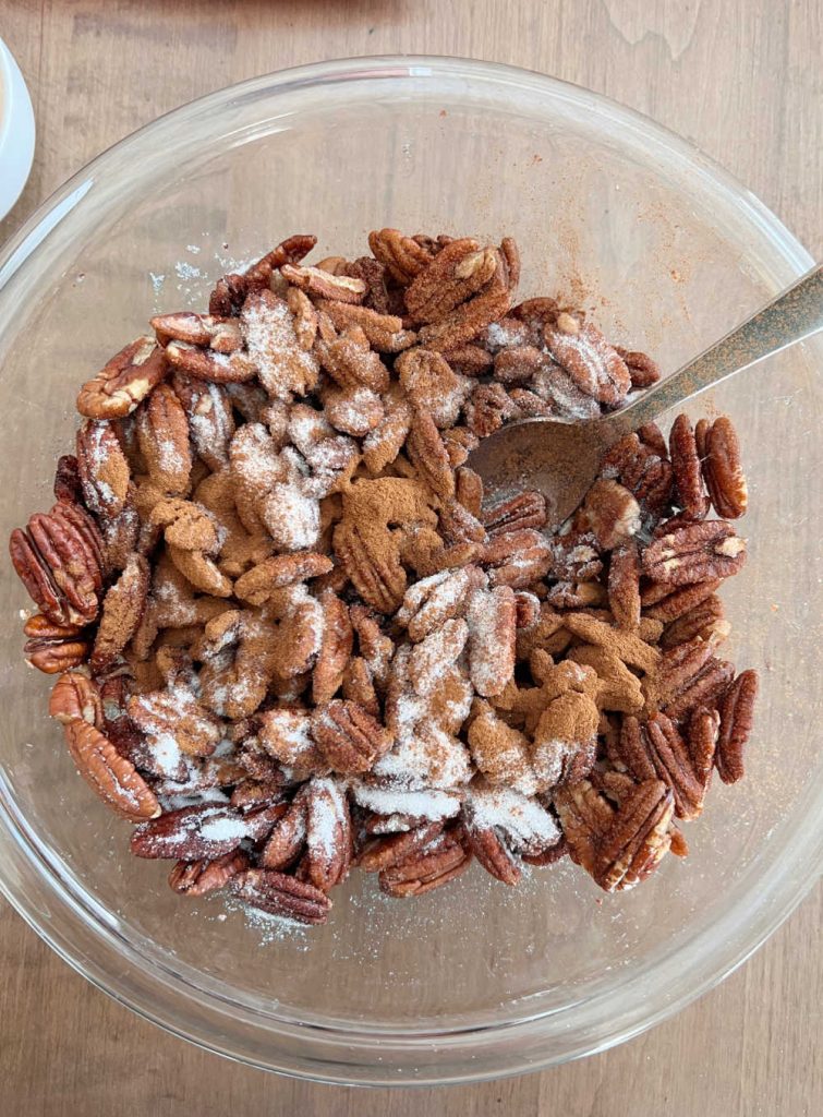 pecans with cinnamon and sugar in mixing bowl