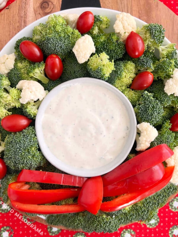 christmas wreath vegetable platter made with broccoli, cauliflower, tomatoes and red pepper strips with dip