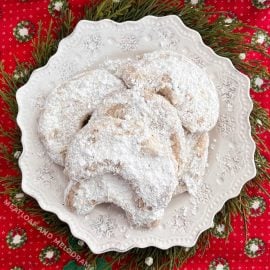 walnut crescent cookies with powdered sugar on white plate