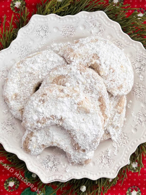 walnut crescent cookies with powdered sugar on white plate