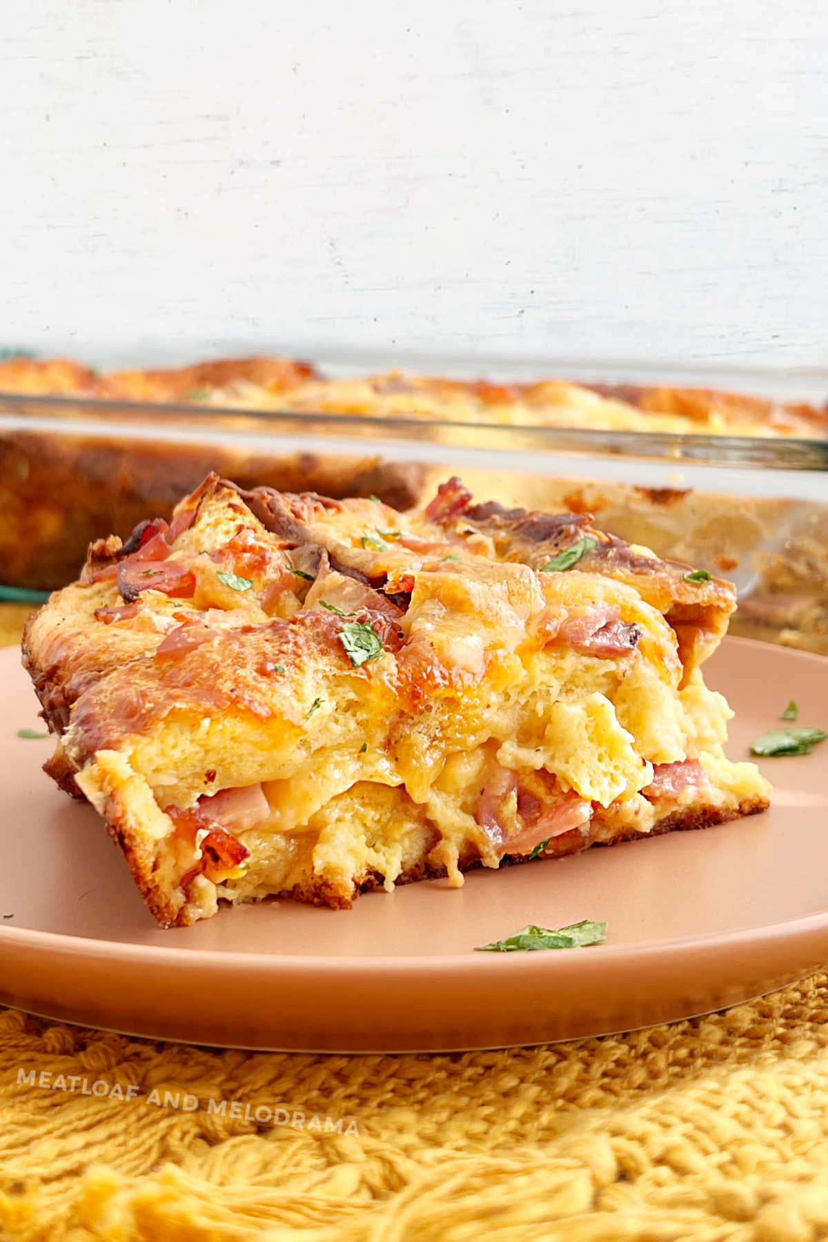 slice of ham and cheese breakfast strata on the table with parsley