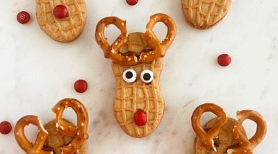 nutter butter reindeer cookies with pretzel antlers on marble cake stand