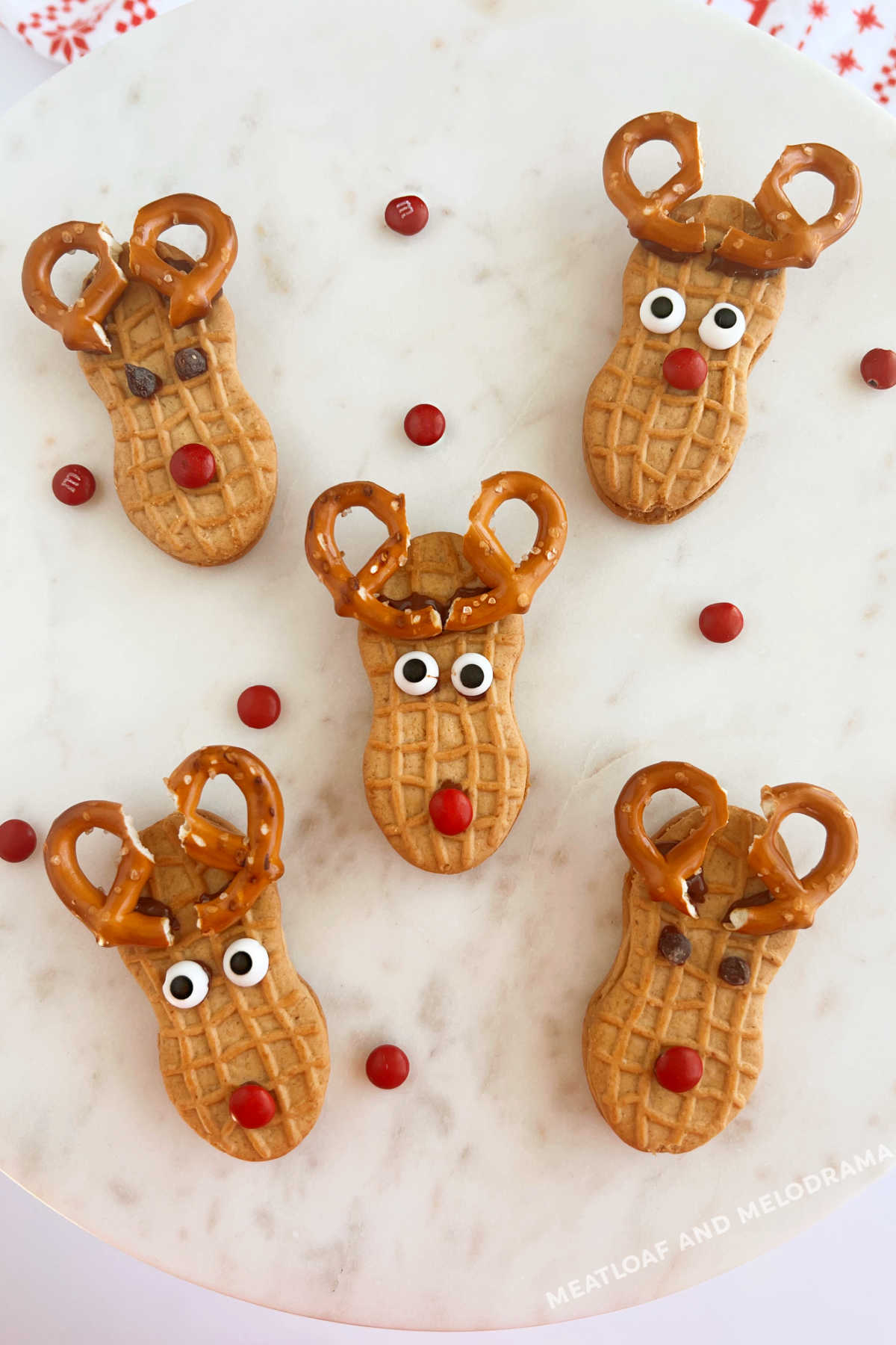 nutter butter reindeer cookies with pretzel antlers and red candy noses on platter