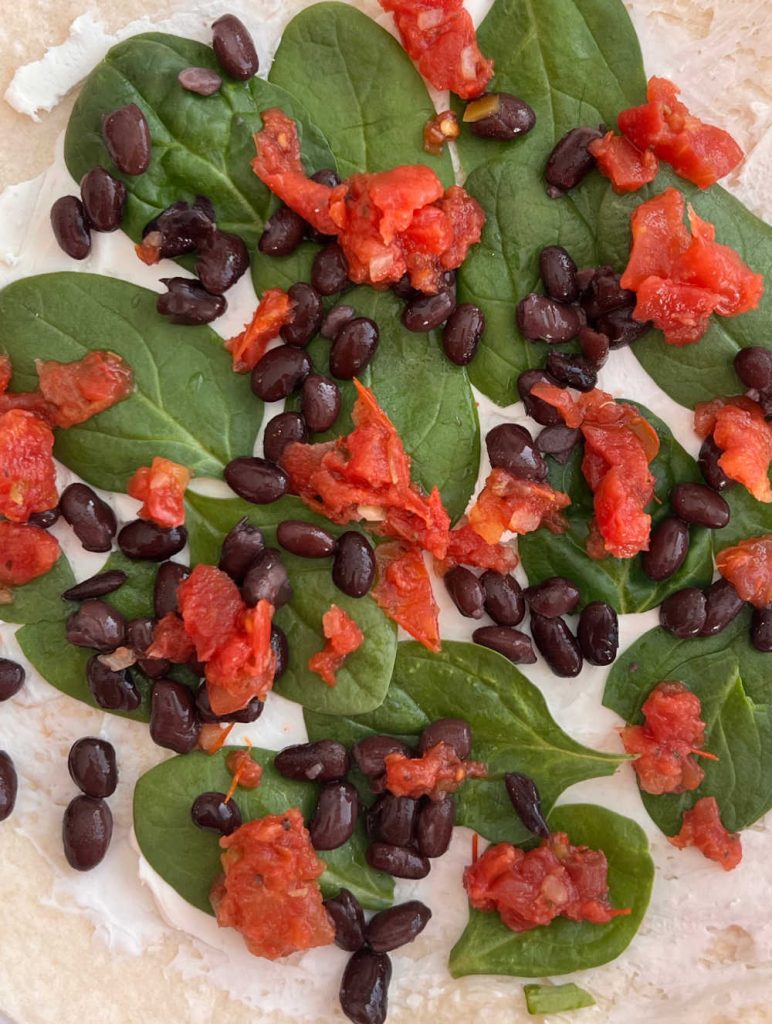 spinach leaves, black beans and rotel tomatoes over cream cheese on tortilla