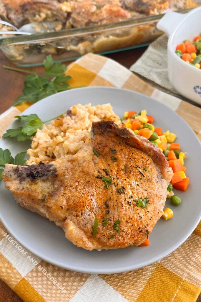baked pork chops and rice with mixed vegetables on the table
