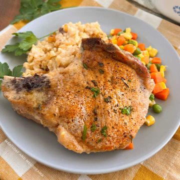baked pork chops with rice and mixed vegetables on a plate