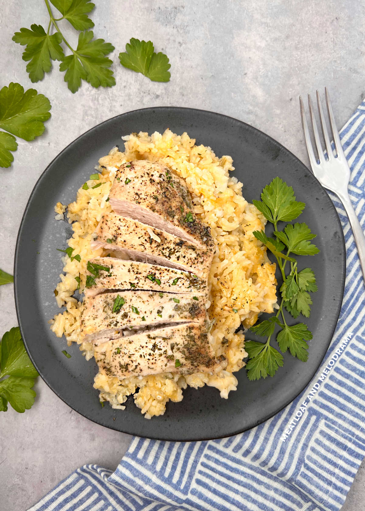 baked chicken and rice on a black plate with parsley