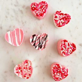 pink and white homemade chocolate candy hearts with sprinkles on marble background