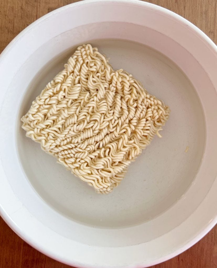 uncooked instant ramen noodles in bowl of water