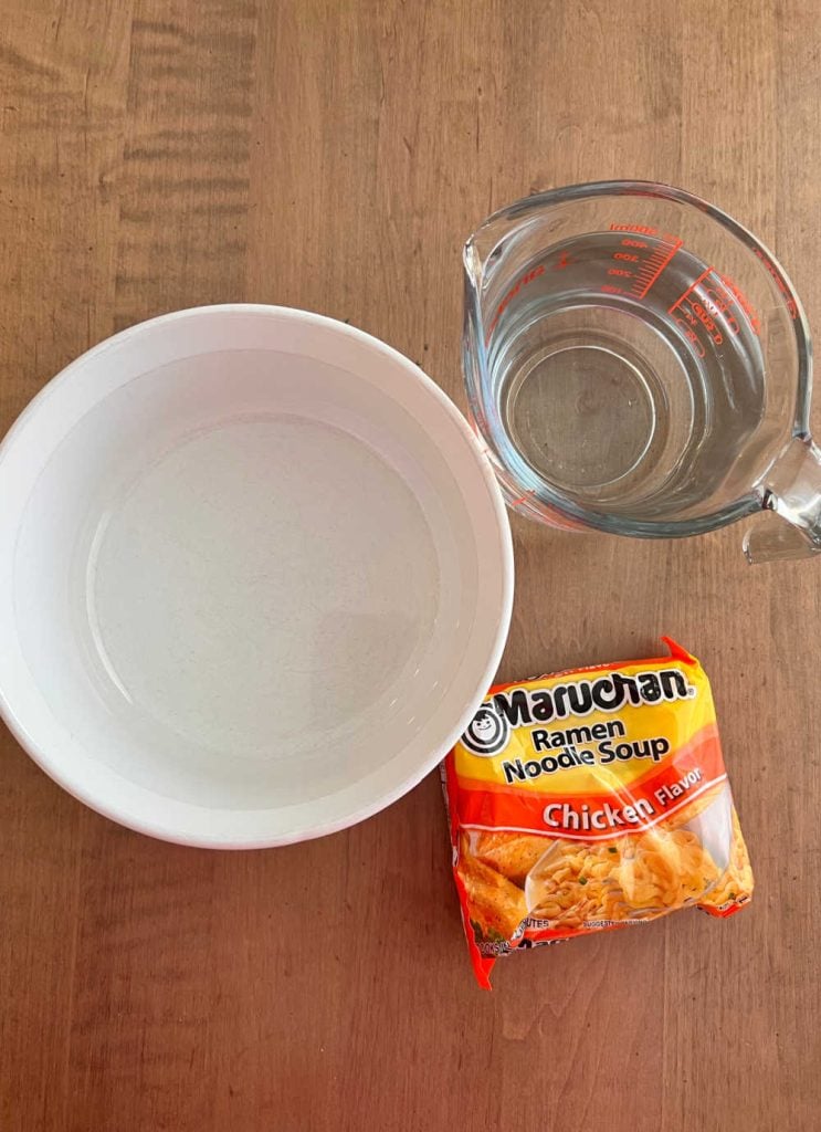 instant ramen packet with white bowl and water on the table