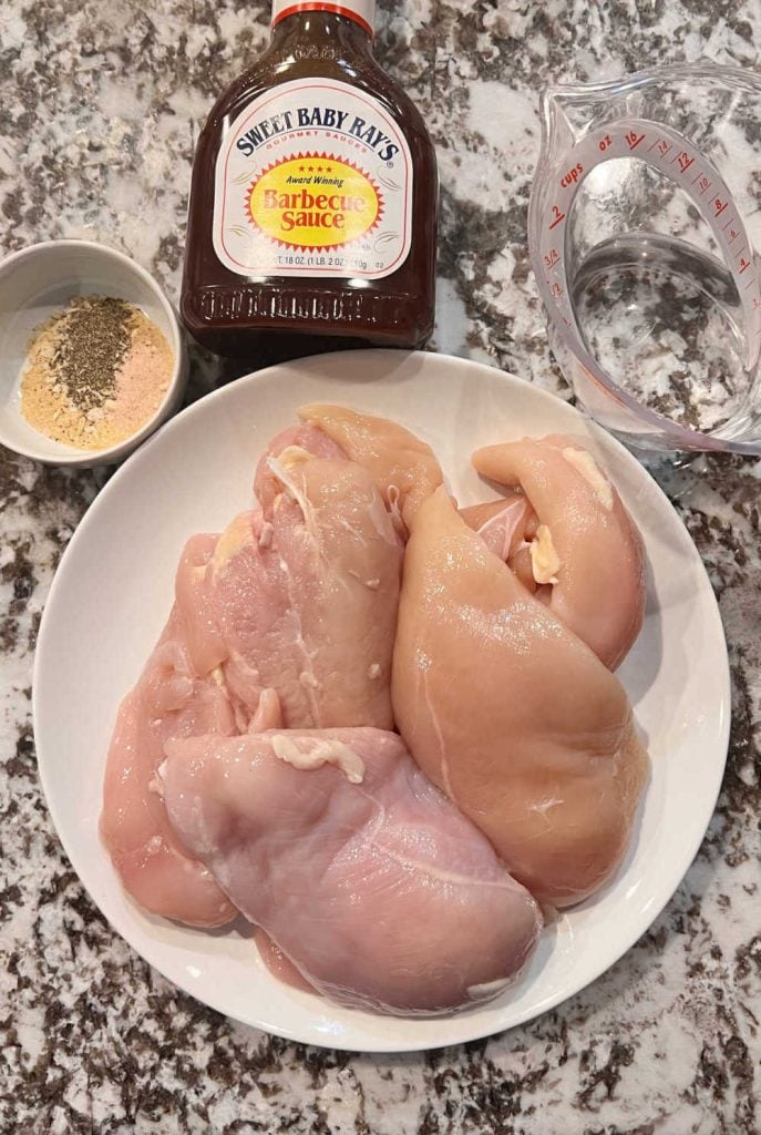chicken breasts, seasoning, sweet baby ray's bbq sauce and water on the counter
