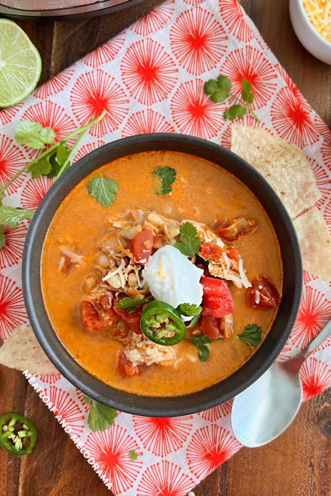 instant pot chicken enchilada soup topped with sour cream, jalapeno slices and cilantro