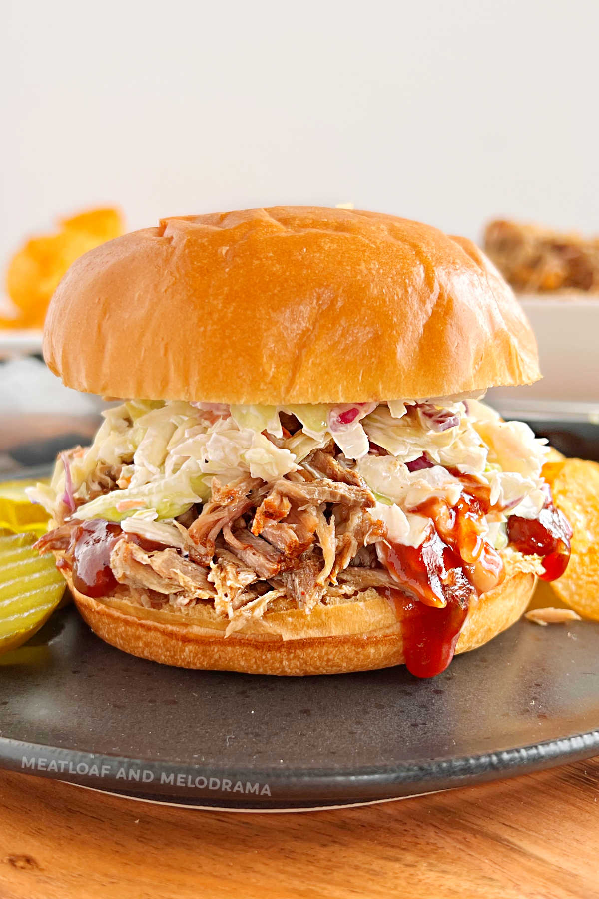 instant pot pulled pork sandwich with coleslaw and bbq sauce on a black plate
