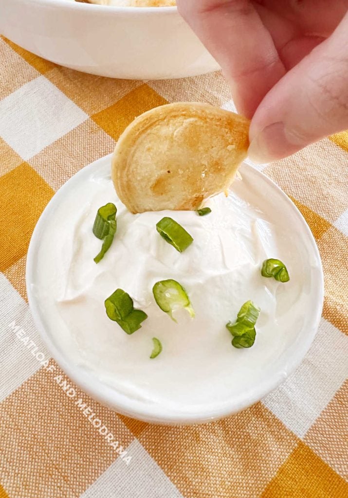 hand dipping air fried pierogi in sour cream