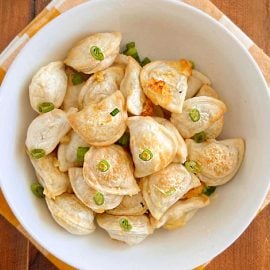 air fryer pierogies with sliced onions in a white bowl