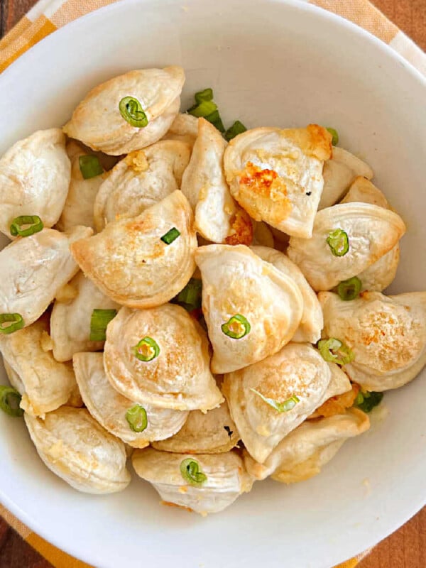 air fryer pierogies with sliced onions in a white bowl