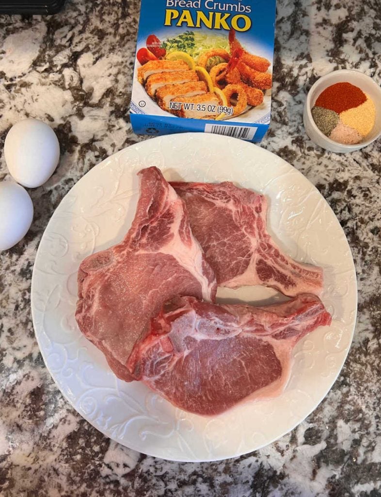 bone in pork loin chops, eggs, panko bread crumbs and seasoning on counter