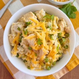 bowl of instant pot cheesy chicken and rice with peas on the table