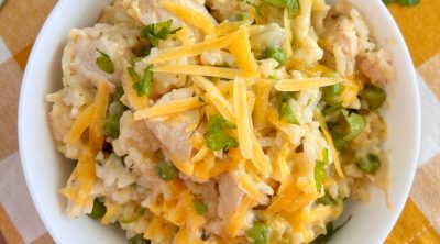 bowl of instant pot cheesy chicken and rice with peas on the table