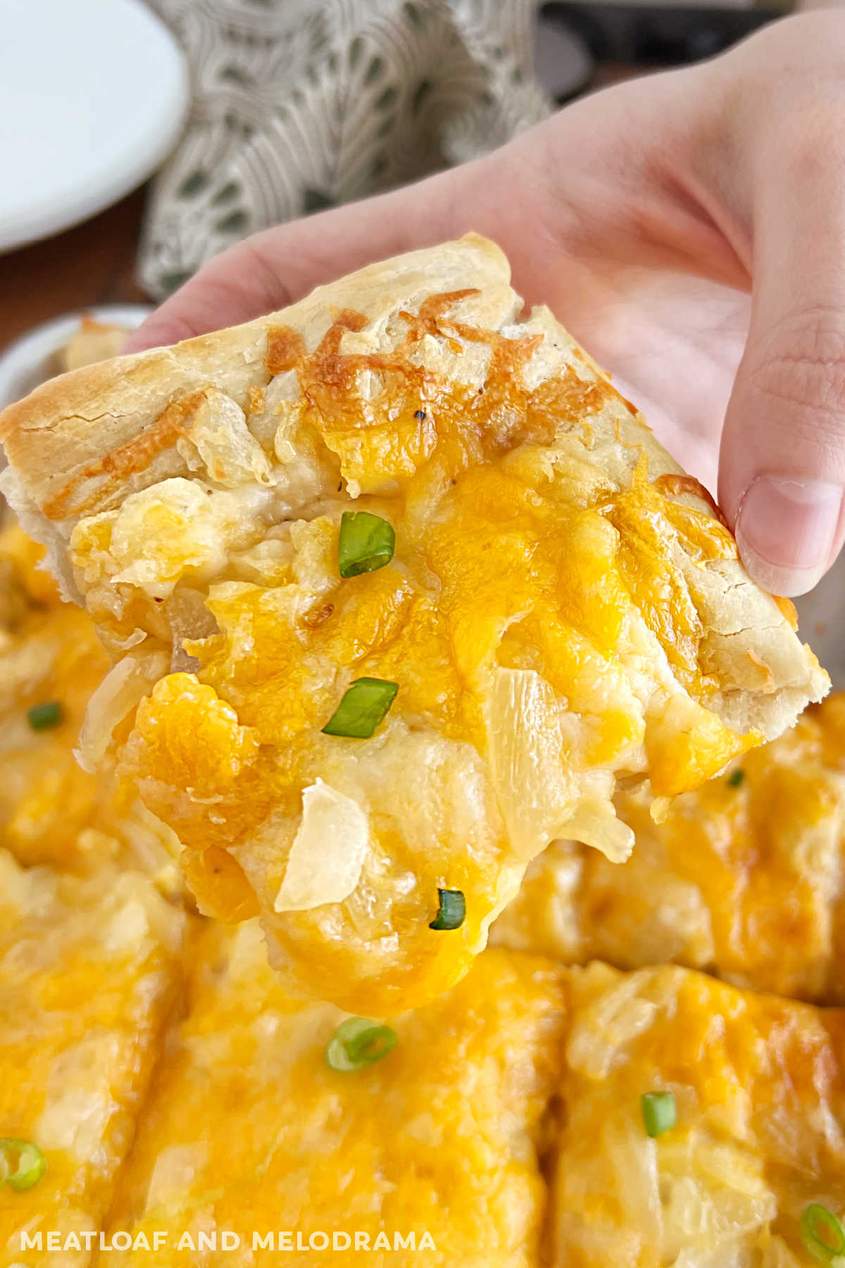 slice of pierogi pizza (pagach) with onions in hand