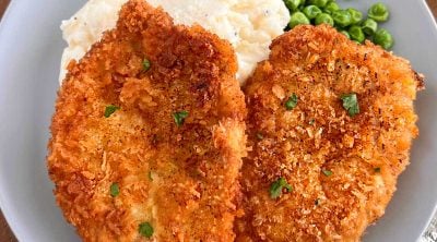 polish breaded pork chops (kotlet schabowy) with mashed potatoes and peas on a plate