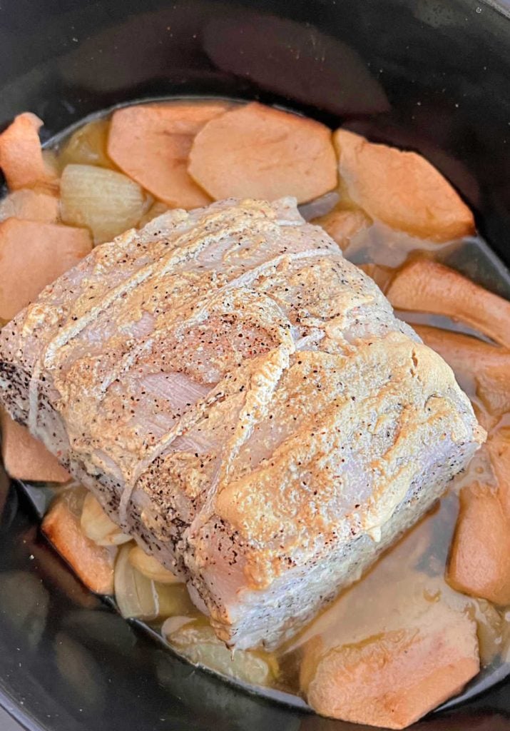 slow cooked pork roast with apples, onions and garlic in the crock pot