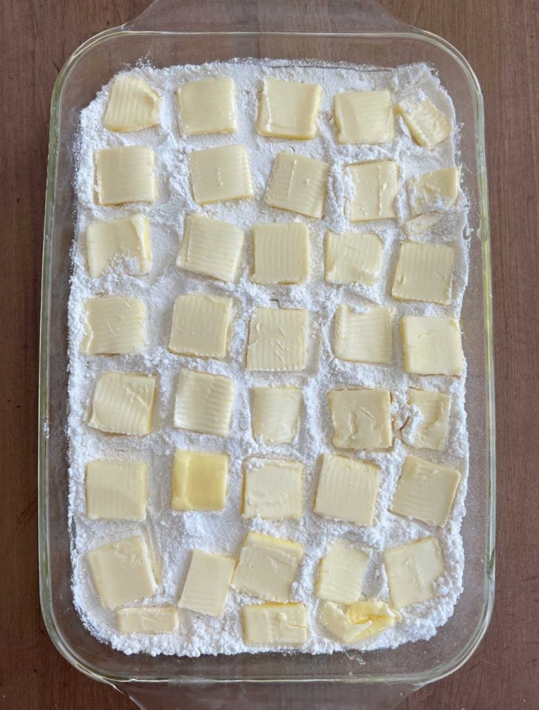 pats of butter on cake mix in baking dish
