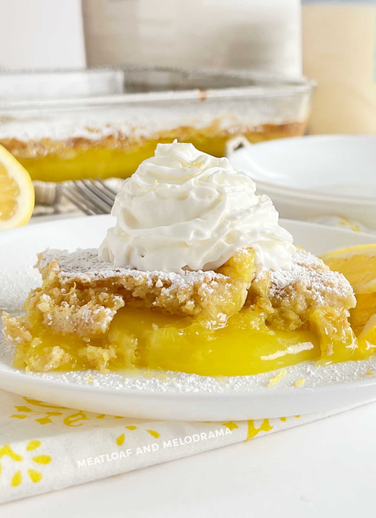 lemon dump cake with whipped cream on a white plate