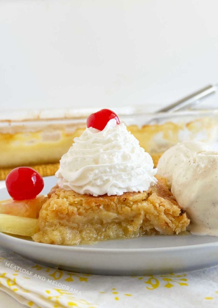 slice of pineapple dump cake with ice cream and maraschino cherries on a plate