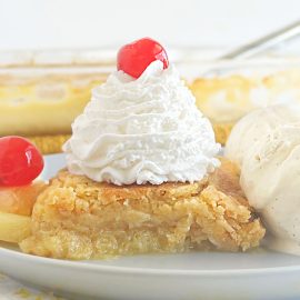 pineapple dump cake with whipped cream and maraschino cherry on top