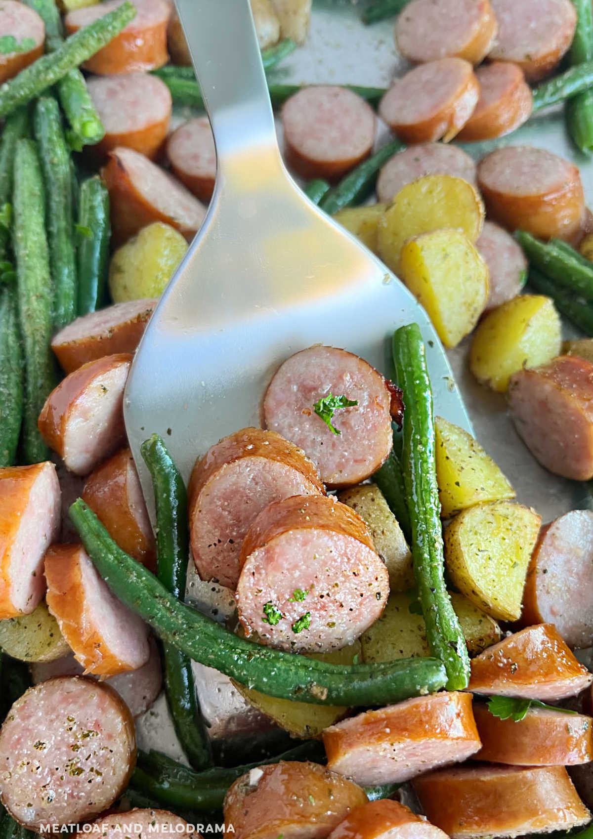 smoked sausage and potatoes with fresh green beans on metal spatula