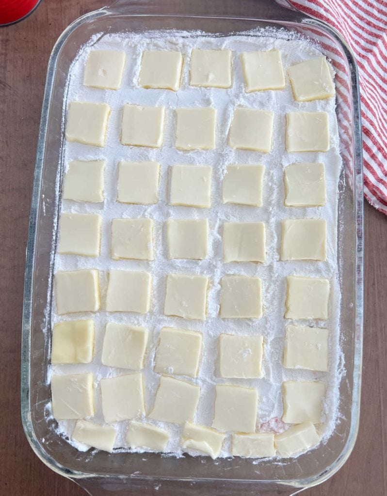 slices of butter over dry cake mix in baking pan