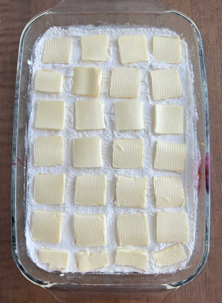 pats of butter on cake mix in baking pan