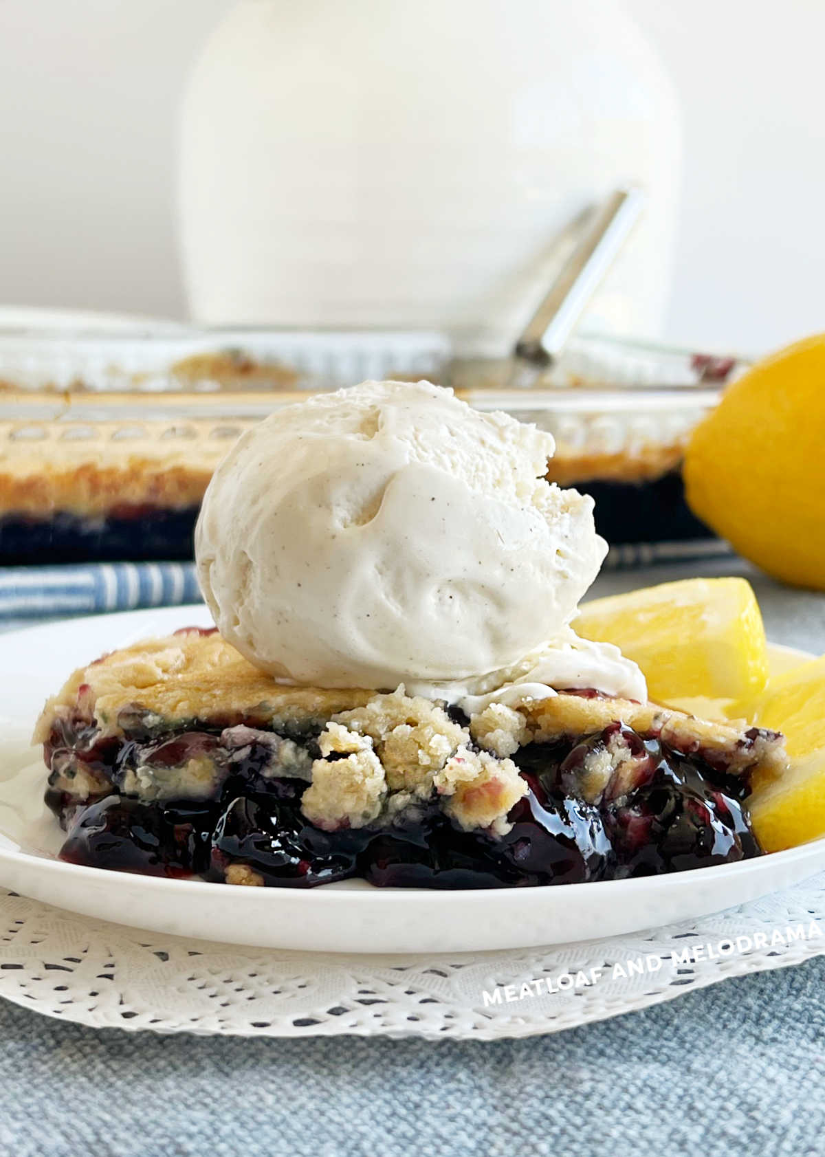 blueberry dump cake dessert on plate with vanilla ice cream and lemon slices