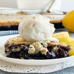 slice of blueberry dump cake with scoop of vanilla ice cream on top and lemon slices