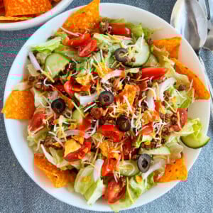 dorito taco salad with ground beef taco meat and catalina dressing and doritos on the table