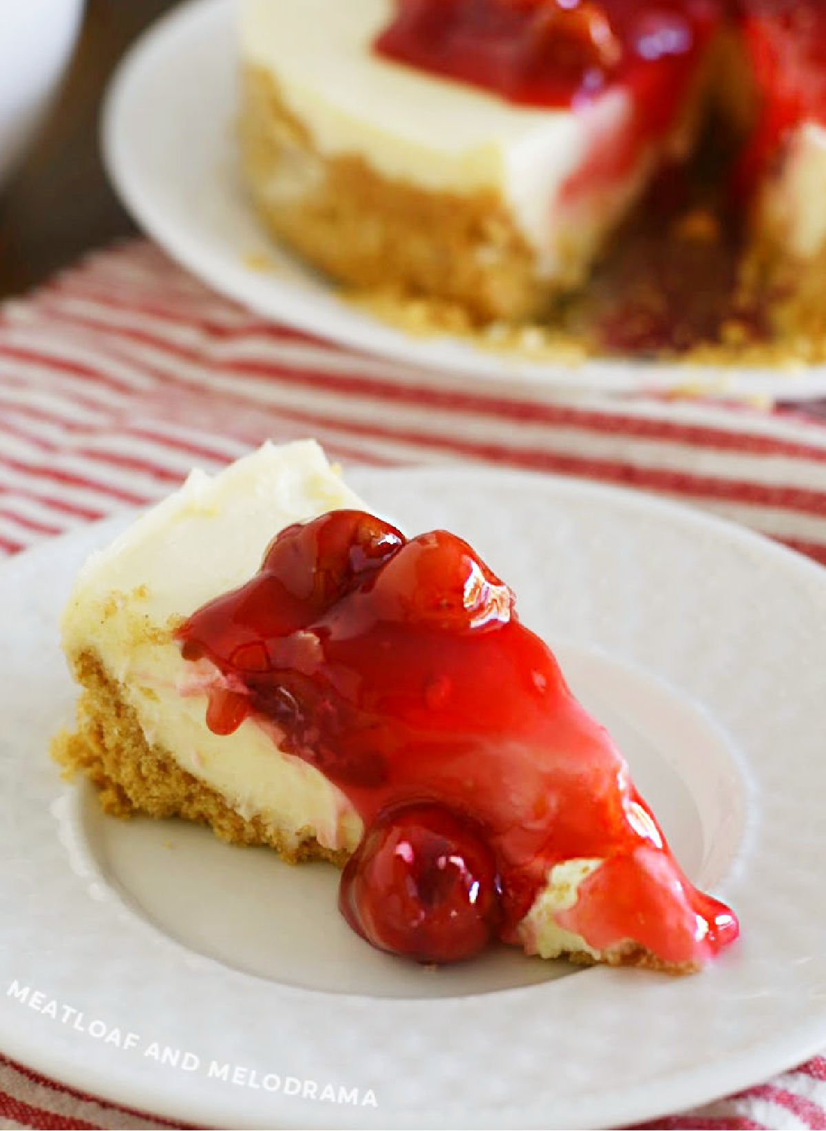 slice of instant pot cheesecake with graham cracker crust and cherry pie filling on top