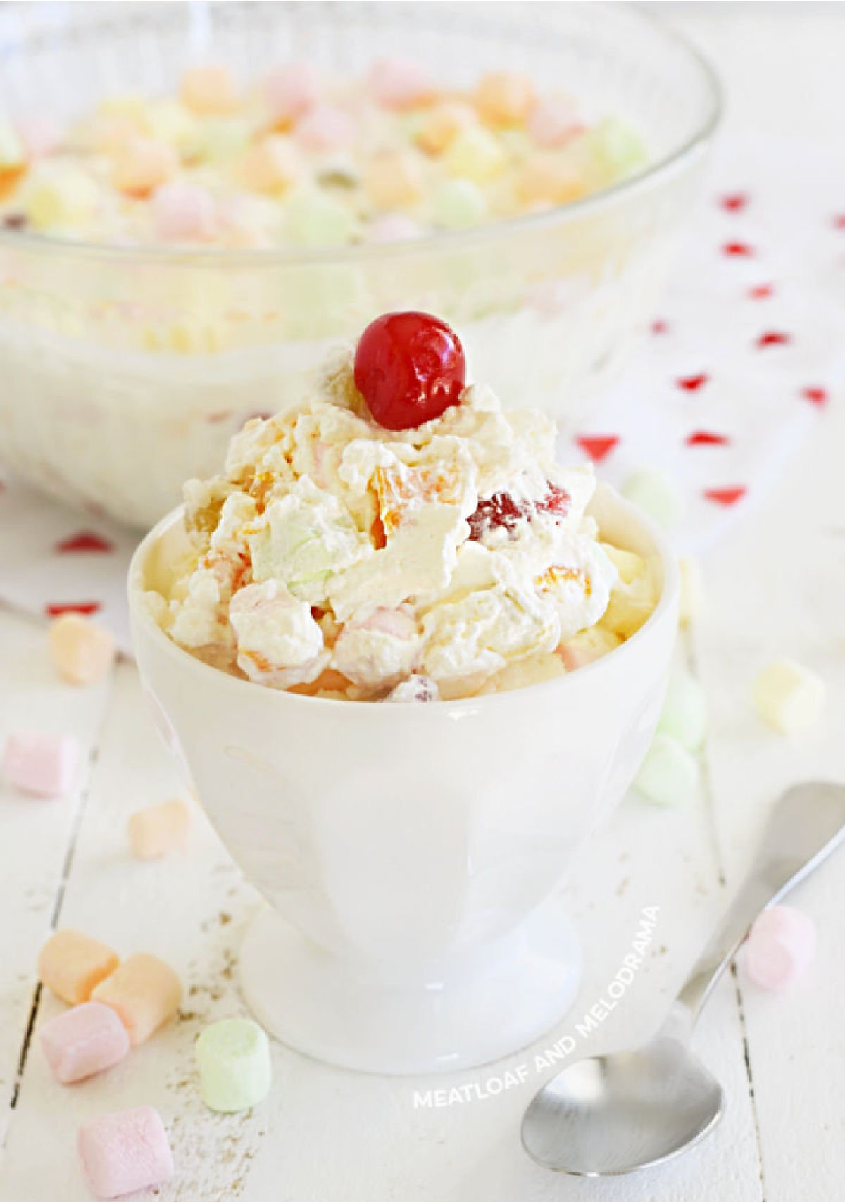 fruit salad recipe with cool whip and cherry in white dish on the table