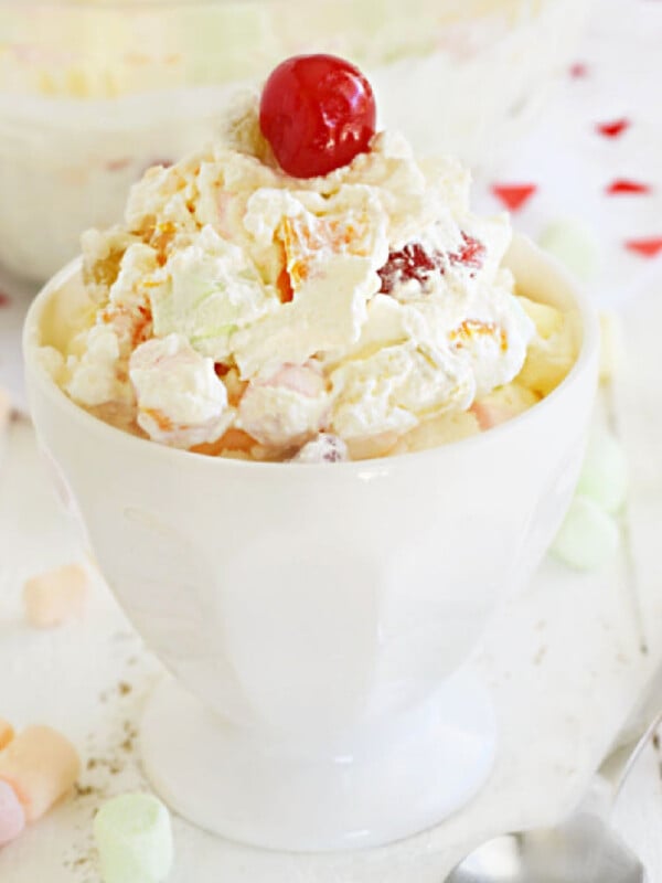 marshmallow fruit salad with cool whip and maraschino cherry in a dish