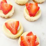 mini cheesecakes with graham cracker crust and fresh strawberry slices on top