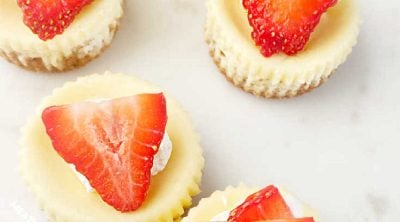 mini cheesecakes with graham cracker crust and fresh strawberry slices on top