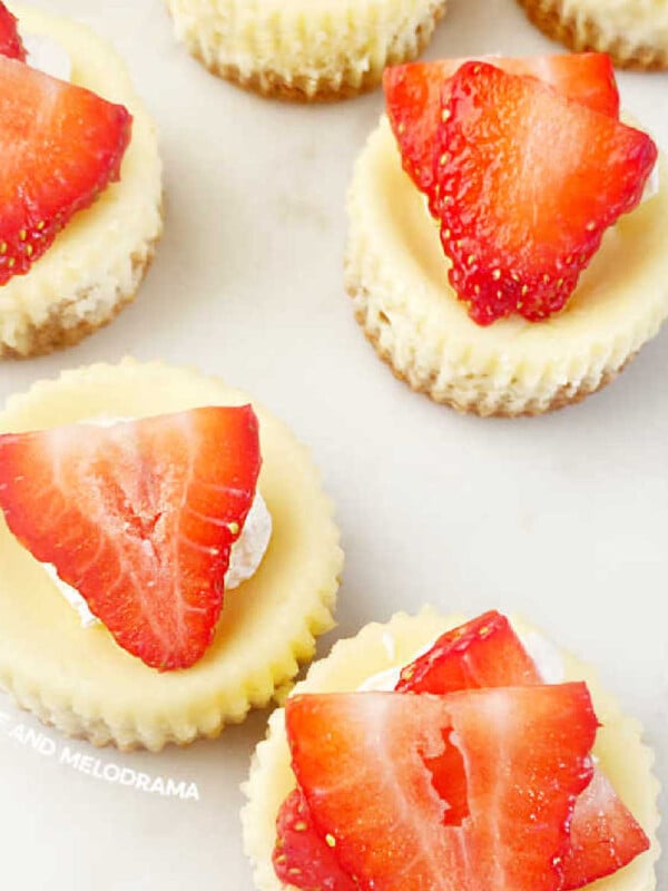mini cheesecakes with graham cracker crust and fresh strawberry slices on top