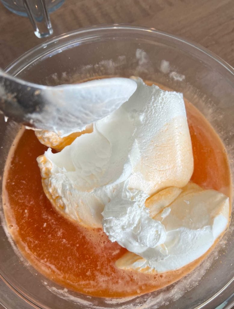 cool whip and orange jello with water in a mixing bowl