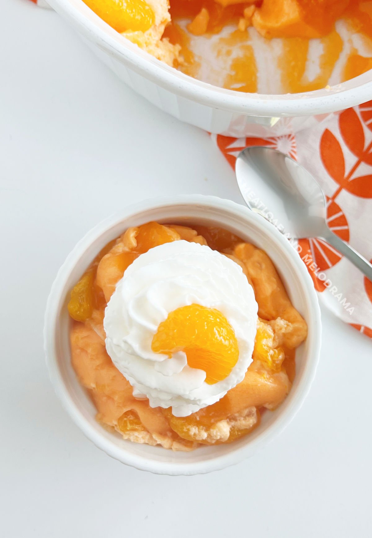 bowl of orange jello salad with mandarin orange slice on the table