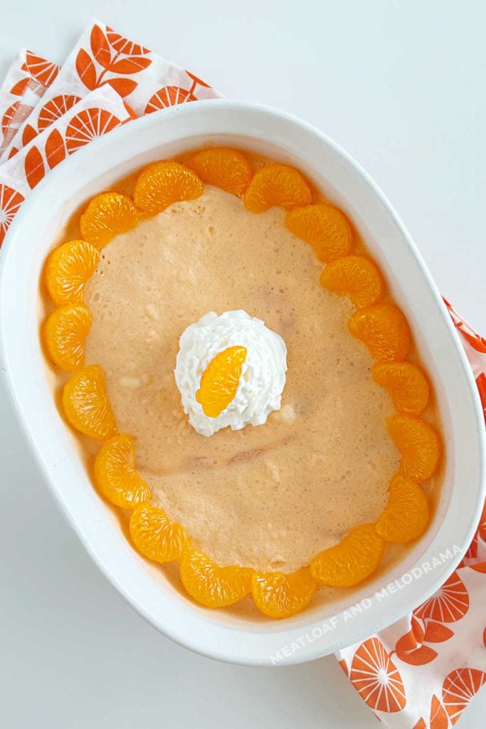 orange jello salad with mandarin oranges and whipped cream in serving dish