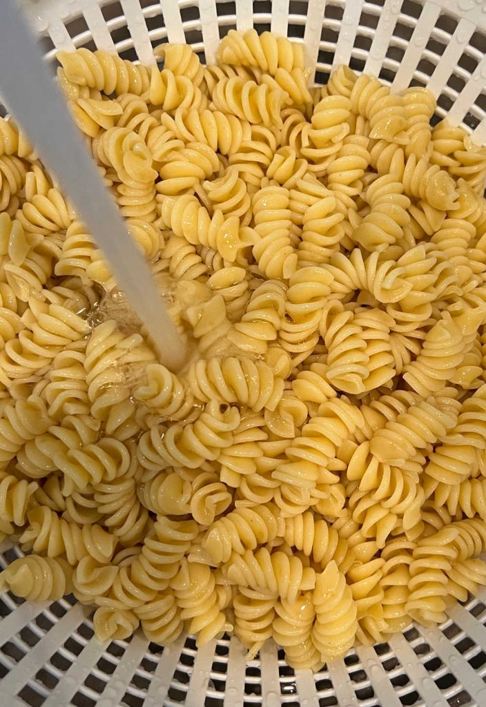 rinse cooked rotini pasta in colander with cold water